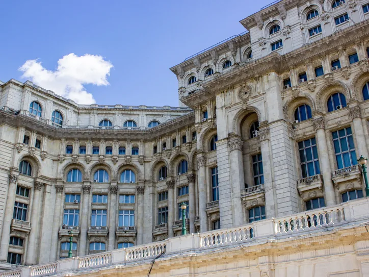 Ornate facade of Palace of the Parliament in Bucharest under clear blue sky.