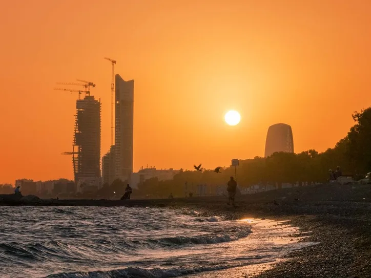 Breathtaking sunset view over Limassol beach with urban skyline and orange sky.