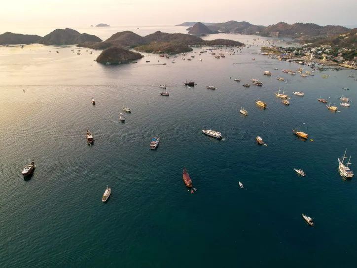 Aerial view of boats scattered across Labuan Bajo's scenic waters at sunset.