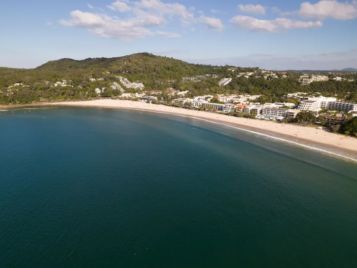 Stunning aerial view of Noosa Heads beach and coastline, showcasing lush greenery and clear blue waters.
