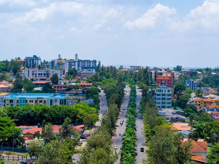 Panoramic view of Kigali cityscape featuring lush greenery and urban development under a sunny sky.