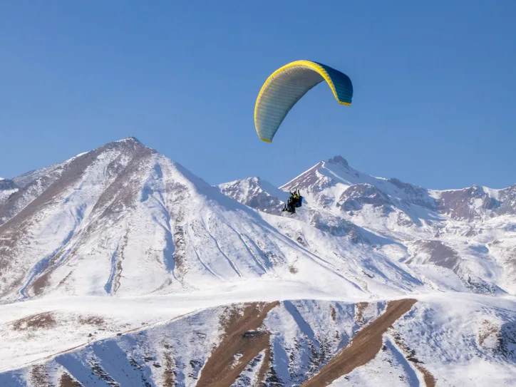 Experience the thrill of paragliding over snow-capped Gudauri mountains in Georgia.