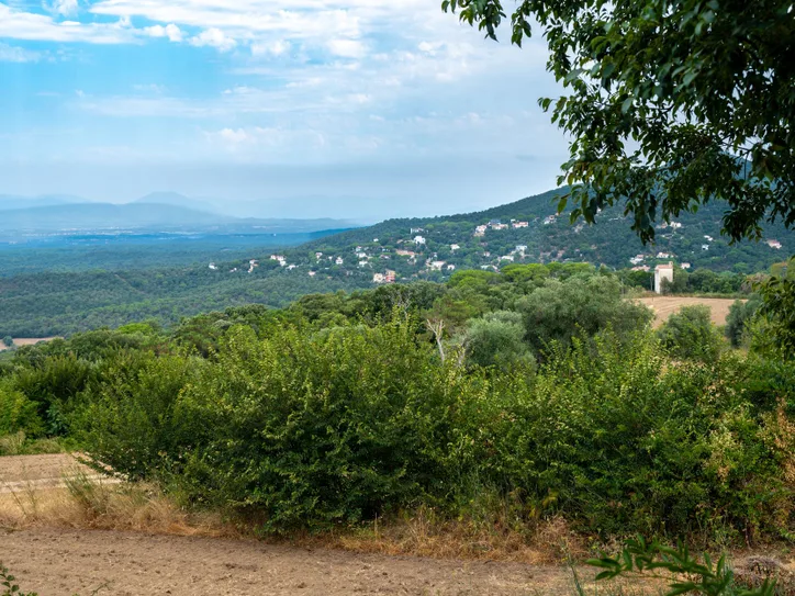 Expansive view of Girona's lush landscape and hillside houses captured under a serene sky.