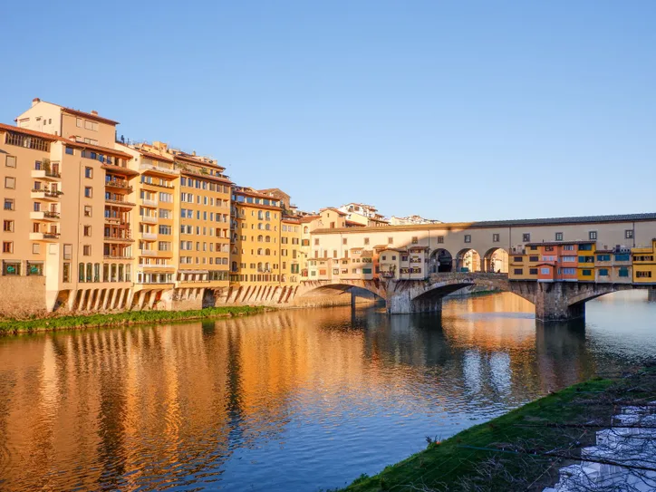 Beautiful sunset view of Ponte Vecchio reflected on the Arno River in Florence, Italy.