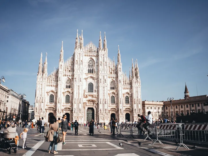 Capture of the majestic Milan Cathedral, showcasing its stunning Gothic architecture in a lively city square.