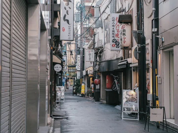 Capture of a quiet, narrow street in Tokyo, showcasing traditional Japanese architecture and vibrant signage.