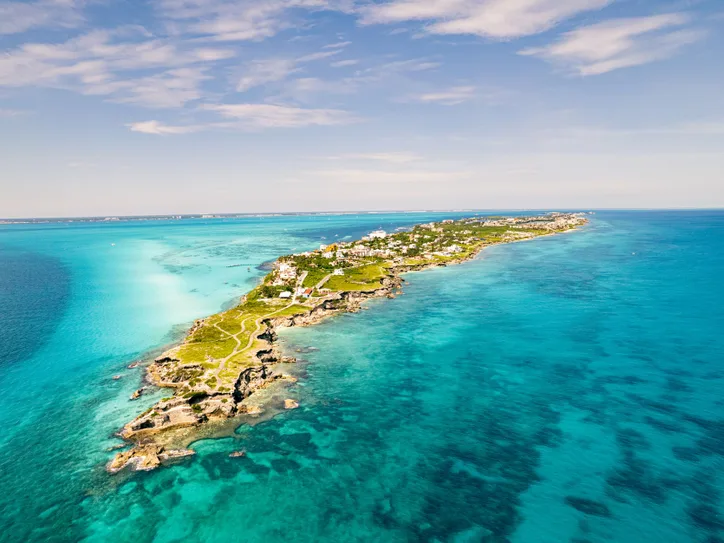 Breathtaking aerial view of Isla Mujeres, vibrant turquoise waters, and lush greenery in the Caribbean Sea.