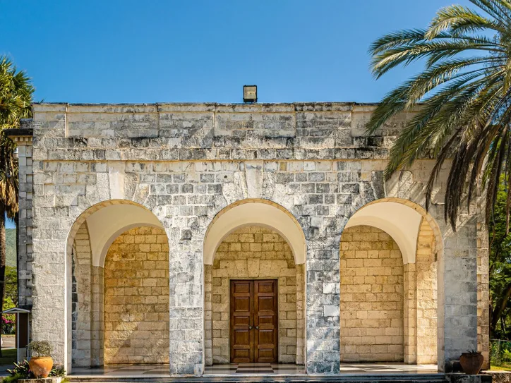 Old stone structure with arched entrance surrounded by palm trees in Kingston, Jamaica.