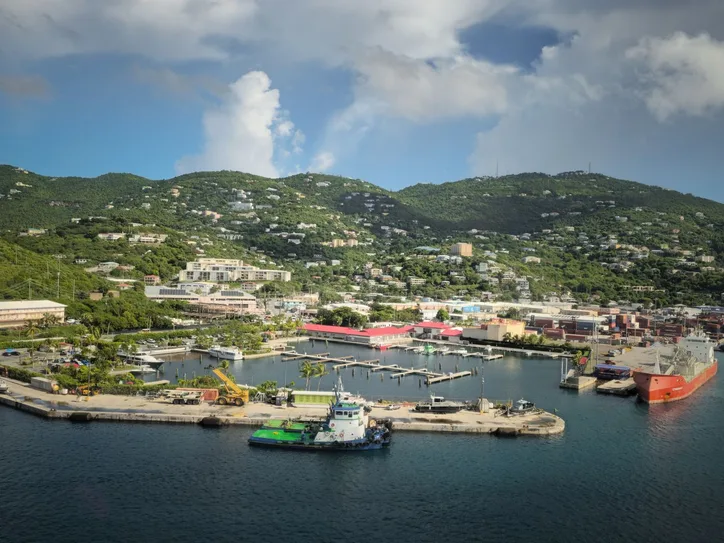 A scenic aerial view of Charlotte Amalie Harbor on St. Thomas, featuring lush green mountains and clear blue water.
