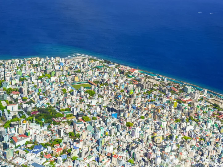 Colorful aerial view of Malé, Maldives showcasing cityscape and ocean coastline.