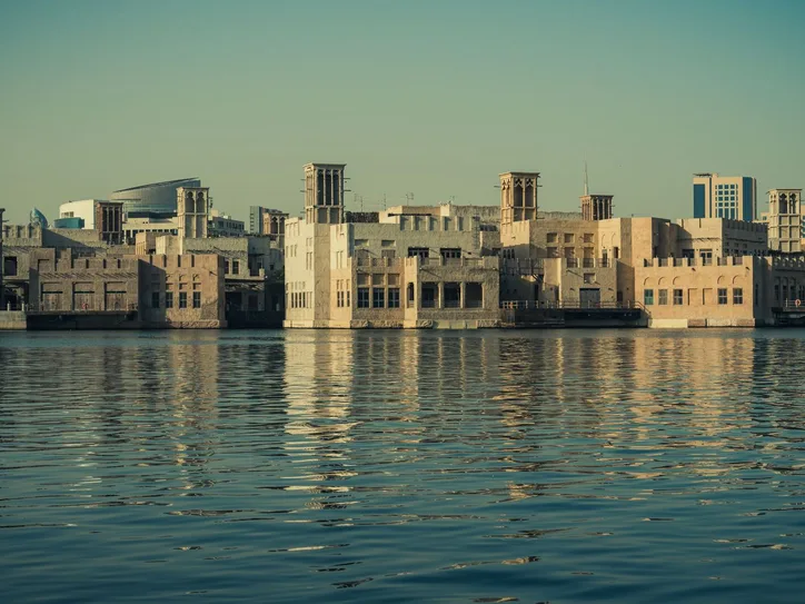 Scenic view of modern architecture reflecting on the Dubai Creek waters, showcasing Dubai's waterfront skyline.