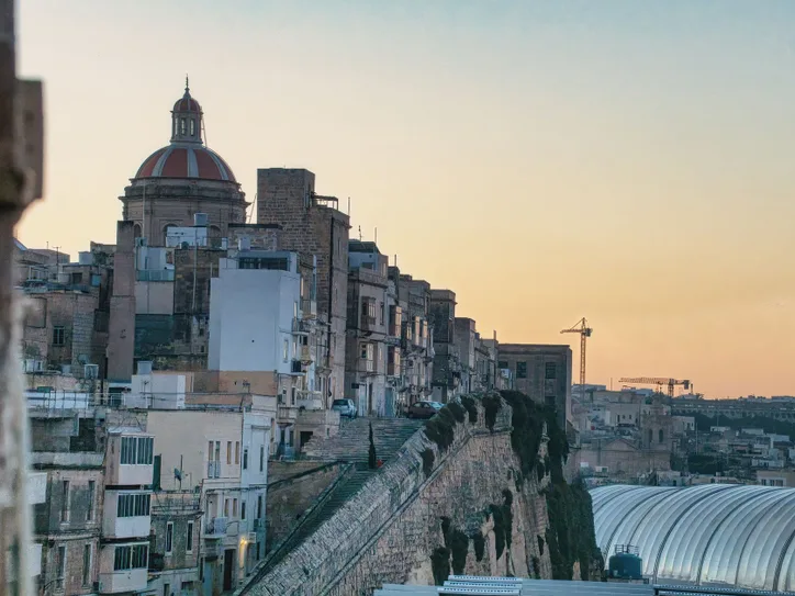 View of Valletta's historic skyline with a dome at sunset, showcasing architectural beauty.