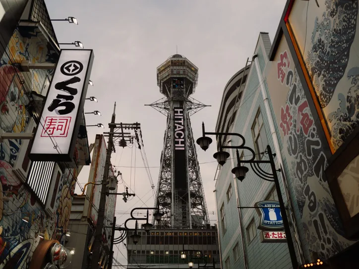 View of Osaka's Tsutenkaku Tower amidst colorful street art and urban architecture, a blend of tradition and modernity.