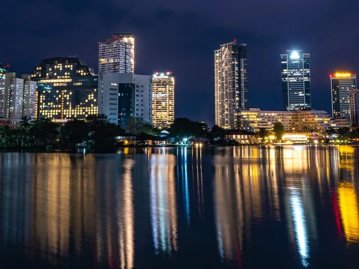 Stunning night view of Colombo skyline reflecting in serene water. Captivating city lights create a vibrant atmosphere.