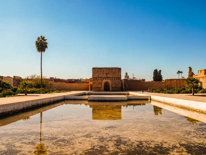El Badi Palace in Marrakech under a clear blue sky with a reflecting pool in the foreground.