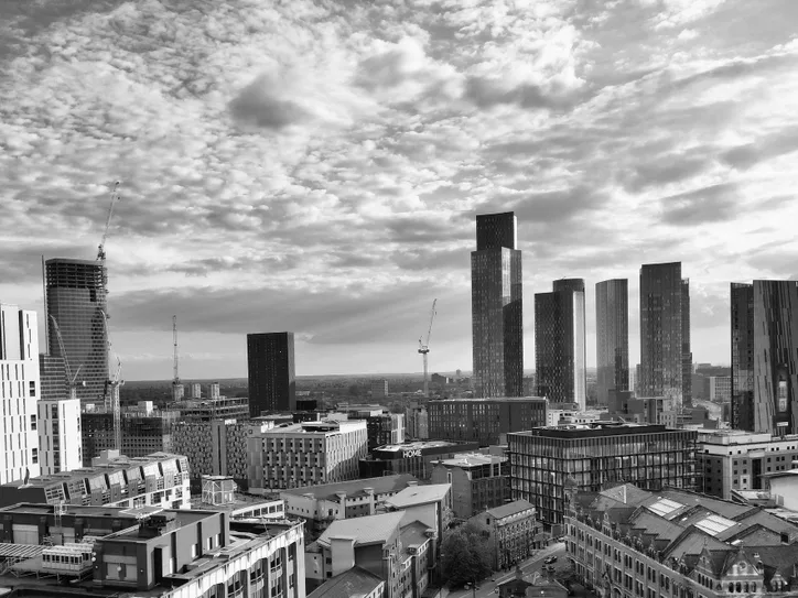 A monochrome cityscape showcasing the modern architecture of Manchester, UK under a dramatic sky.
