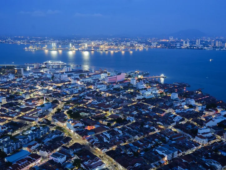 Captivating night aerial skyline of Penang, Malaysia, showcasing urban lights and sea view.