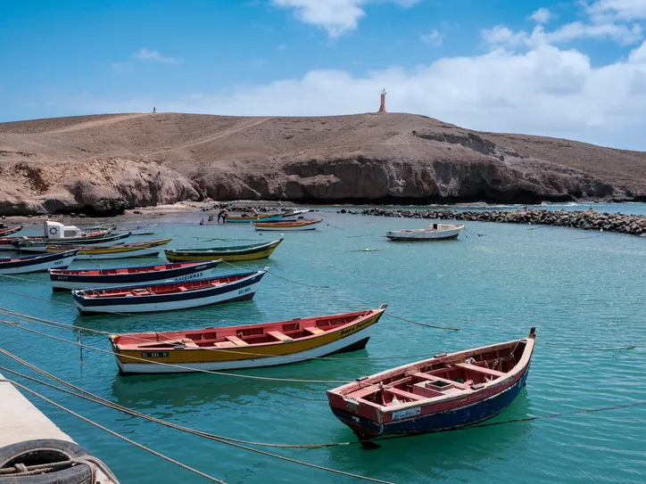 Lively scene of colorful fishing boats anchored in the serene waters of Pedra Lume, Sal, Cabo Verde.