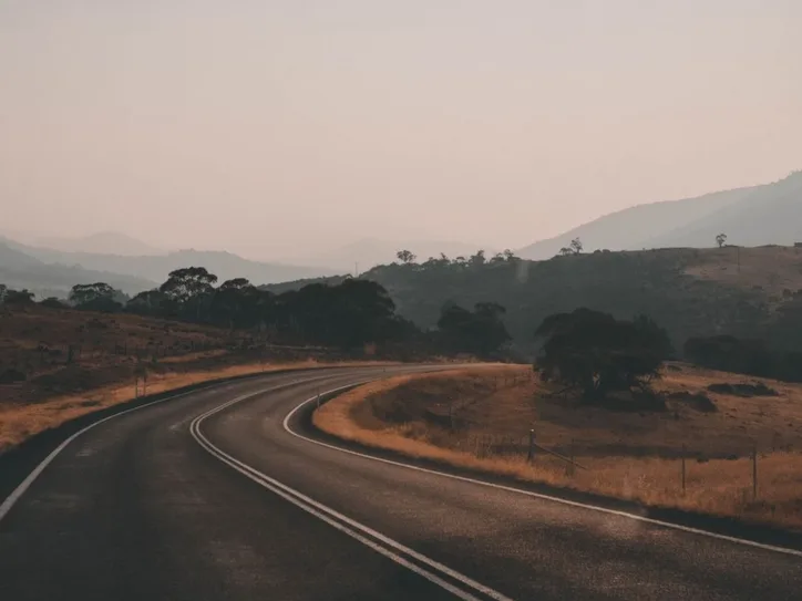 A picturesque highway winding through Thredbo's serene landscape during sunset in New South Wales, Australia.