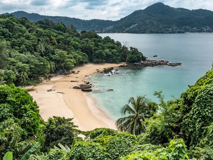 Scenic view of a tranquil tropical beach cove in Phuket surrounded by lush greenery.