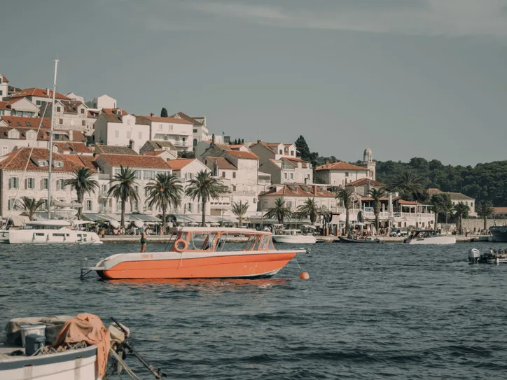 View of Hvar, Croatia's charming coastal cityscape with orange motorboat and yachts in the harbor.