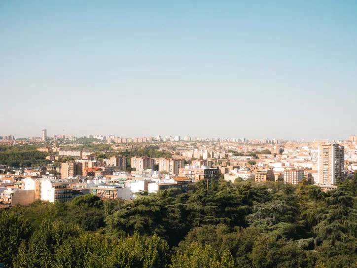 Elevated panoramic view of Madrid's urban landscape with lush greenery and clear skies.