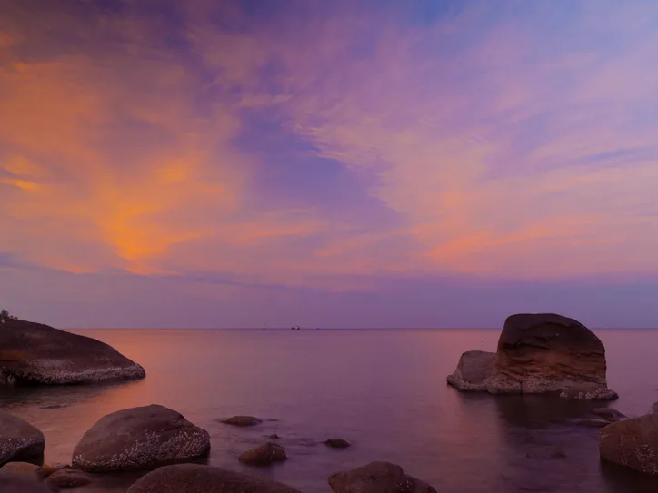 Stunning sunset view over the rocky shores of Ko Tao, Thailand, with vibrant clouds.