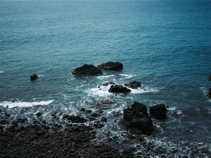 A breathtaking view of the rocky coastline and deep blue ocean in Jacó, Costa Rica.