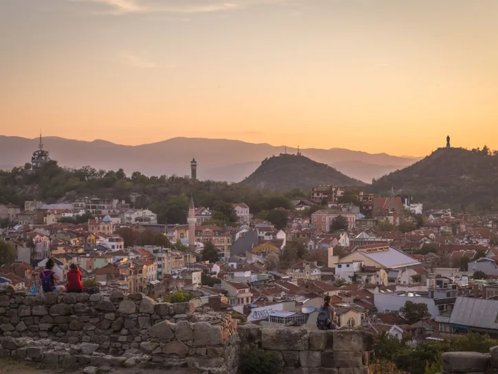 Beautiful sunset view of Plovdiv, Bulgaria, showcasing ancient ruins and distant mountains.